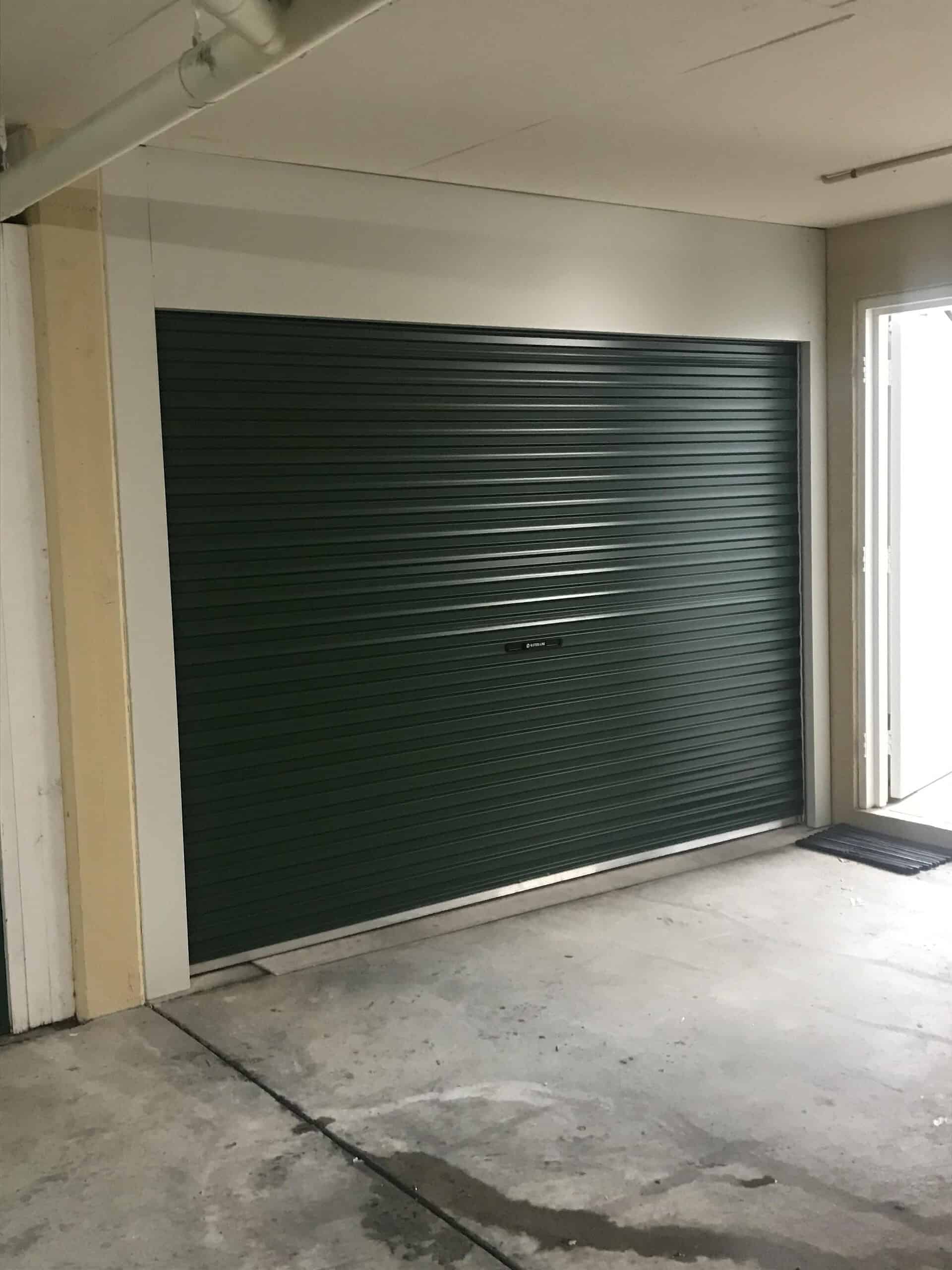 Green steel roller shutter inside a workshop